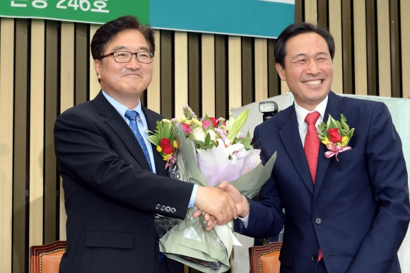 16일 오전 서울 영등포구 여의도 국회에서 진행된 제20대 국회 더불어민주당 제2기 원내대표 선거에서 원내대표로 선출된 우원식(왼쪽) 의원이 우상호 전 원내대표로부터 꽃다발을 받고 있다.  이종원 선임기자 jongwon@seoul.co.kr