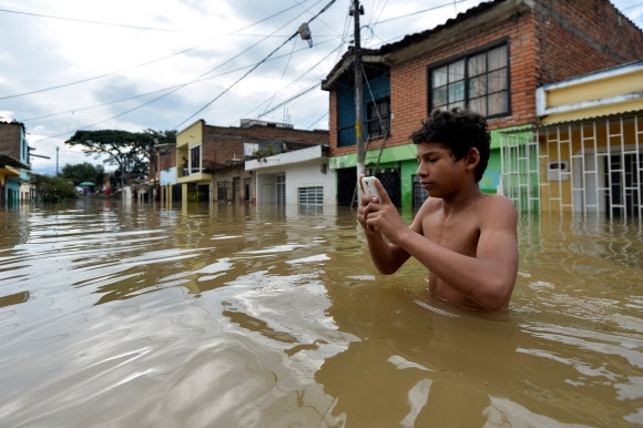 홍수 속에서 휴대전화를 확인하는 콜롬비아의 한 남성