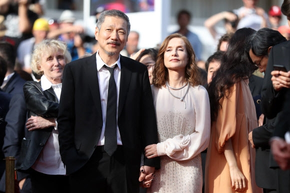 21일(현지시간) 프랑스 칸에서 열린 ‘제70회 칸 영화제’에 참석한 홍상수 감독이 프랑스 여배우 이자벨 위페르의 손을 잡고 입장하고 있다. 오렌지빛 드레스를 입은 김민희(오른쪽)가 이자벨 위페르에 등을 지고 서 있다. AFP 연합뉴스