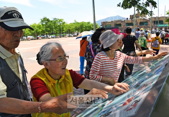 관광지 초입의 점자 안내판을 만져 보고 있는 시각장애인들.