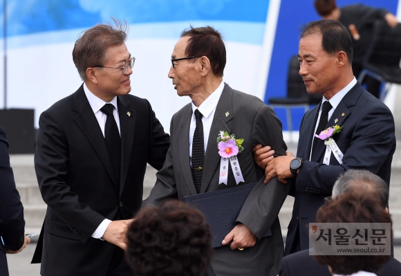 문재인 대통령이 6일 서울 동작구 국립서울현충원에서 열린 제62회 현충일 추념식에서 국가유공자인 박용규씨(가운데)를 부축하고 있다. 오른쪽은 아들 박종철씨.  박윤슬 기자 seul@seoul.co.kr