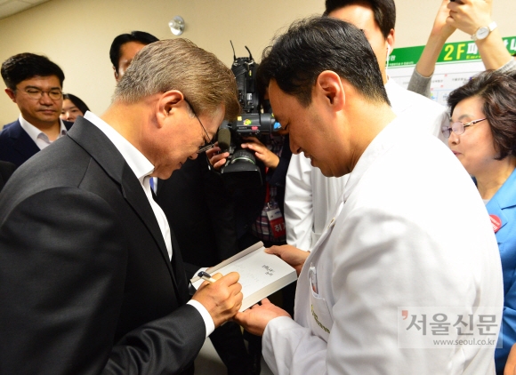 문재인 대통령이 제62회 현충일인 6일 오전 서울 강동구 중앙보훈병원을 방문해 한 병원 관계자가 가지고온 서적  ’전환시대의 논리’에 사인을 하고 있다.  청와대사진기자단