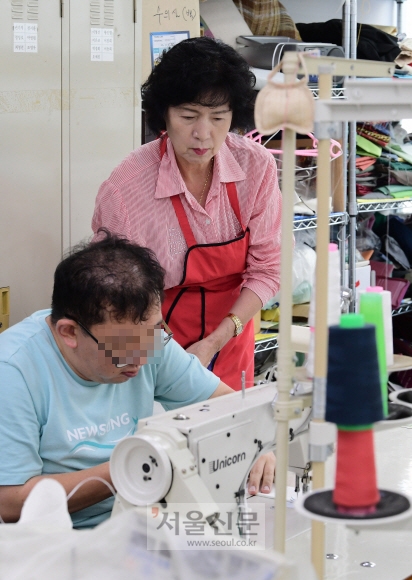서울 강동구 ‘파란마음 복지센터’에서 발달장애인들을 도와 가며 한지(韓紙)로 수의(壽衣)를 만들고 있는 50+세대의 표정이 진지하다.
