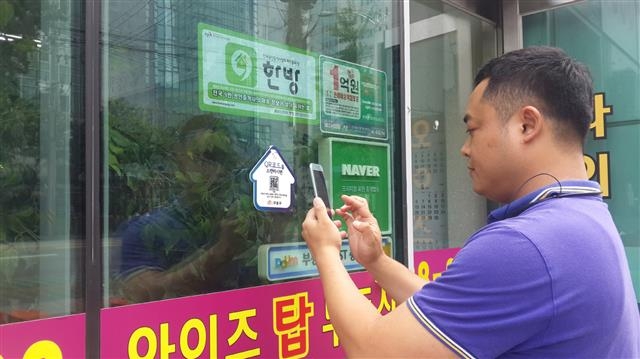 한 주민이 부동산중개업소 앞에서 QR코드를 스캔하고 있다. 구로구 제공
