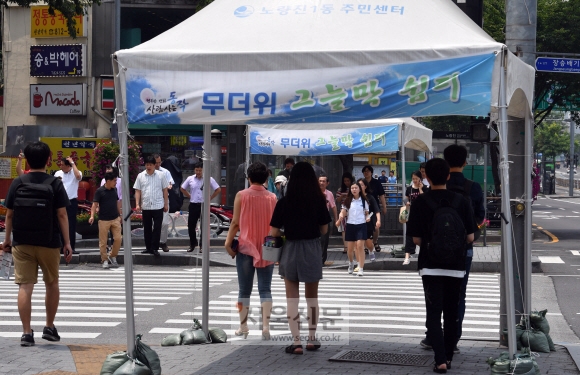 무더위가 찾아온 6일 서울 동작구 노량진의 한 횡단보도 섬에 설치된 그늘막 아래에서 시민들이 신호를 기다리고 있다. 이날 서울의 기온은 34.6도까지 치솟아 올 들어 가장 높은 수치를 보였다. 박지환 기자 popocar@seoul.co.kr