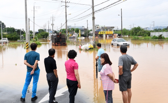 16일 충북 청주시 흥덕구 강내면에서 주민들이 침수된 도로를 바라보고 있다. 시간당 최고 90mm의 물폭탄이 쏟아지는 등 290mm의 폭우가 내린 청주는 1995년 8월 이후 22년만에 홍수 피해를 입었다.  청주 손형준 기자 boltagoo@seoul.co.kr