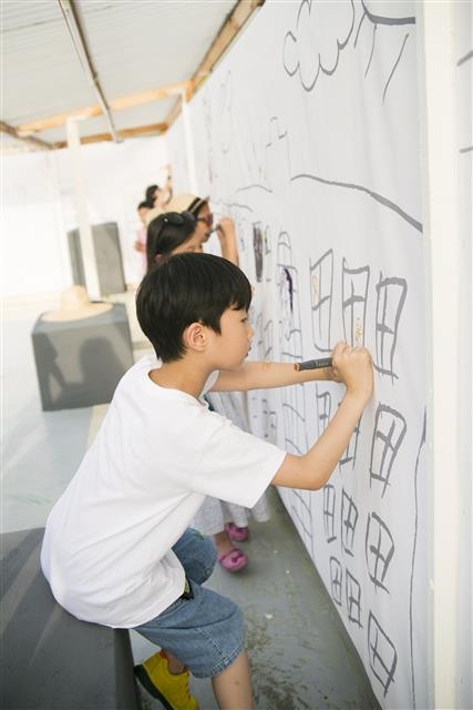 작가가 동네를 돌면서 그린 이미지 위에 벽화놀이를 하는 어린이들.