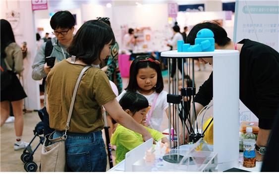 지난 5월 ‘서울 디자인 페스타’에 참가한 ‘팹랩서울’의 3D 프린팅 제품을 방문객들이 체험해 보고 있다. 팹랩서울 제공