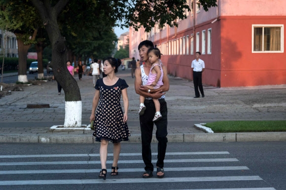 24일 북한 평양 거리에서 가족으로 보이는 부부와 아이가 건널목을 건너고 있다. AFP 연합뉴스