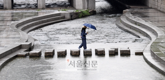 중부지방을 중심으로 국지성 호우가 쏟아진 31일 서울 종로구 청계천에서 한 시민인 우산을 쓰고 돌다리를 건너고 있다.  손형준 기자 boltagoo@seoul.co.kr