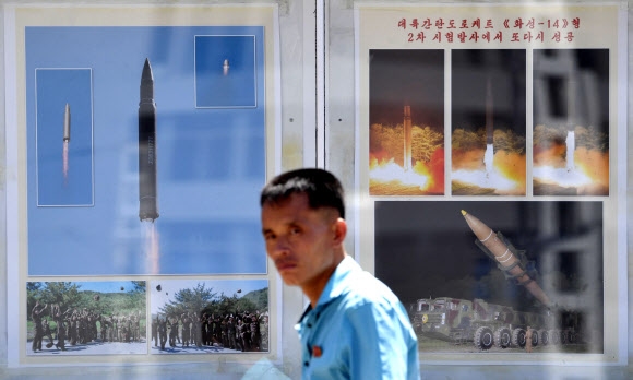 11일 평양역 인근의 미사일 선전물 앞을 지나가는 북한 주민이 카메라를 응시하고 있다. 선전물에는 미사일 발사 장면과 함께 ”대륙간 탄도 로케트 화성-14형 2차 시험 발사에서 또다시 성공”이라는 문구가 적혀 있다.  연합뉴스