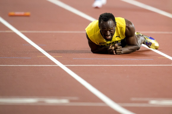 우사인 볼트가 13일 영국 런던의 올림픽 스타디움에서 열린 국제육상경기연맹(IAAF) 세계선수권대회 남자 400m 계주 결선에서 자메이카의 네 번째 주자로 나서 바통을 넘겨받은 뒤 20m를 채 못 가 트랙에 쓰려져 고통스러운 표정을 짓고 있다. 경기 도중 왼쪽 허벅지에 경련이 일어났다고 한다. 고별 인사도 못한 그는 은퇴 번복설에도 휩싸였다. 런던 EPA 연합뉴스