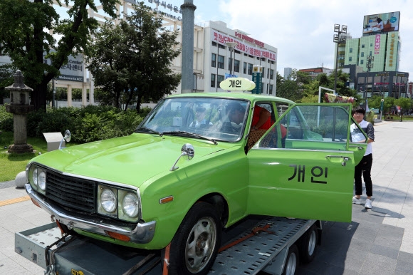 영화 ‘택시운전사’에서 배우 송강호가 몰았던 연두색 택시가 20일 광주 동구 금남로 옛 전남도청 앞에 전시돼 있다. 광주 연합뉴스