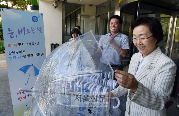 신연희 서울 강남구청장이 지난 25일 청사 로비에서 누구나 공짜로 빌리고 양심껏 반납하는 ‘청렴우산’을 직원들과 살펴보고 있다. 이종원 선임기자 jongwon@seoul.co.kr