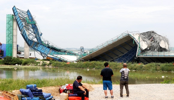 지난 26일 경기 평택 서·남부 지역을 연결하는 평택호 횡단도로의 일부인 평택국제대교(가칭) 건설 현장에서 상판 4개가 붕괴돼 호수 바닥에 떨어진 가운데 주민들이 사고 현장을 살펴보고 있다. 연합뉴스