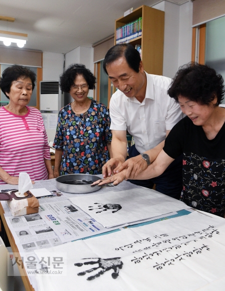 지난 24일 오전 서울 서대문구 홍제2동 주민센터에서 열린 ‘사랑의 손 족자’ 행사에 참석한 문석진(왼쪽 세 번째) 서대문구청장이 화선지에 손도장을 찍는 노인을 돕고 있다. 강성남 선임기자 snk@seoul.co.kr
