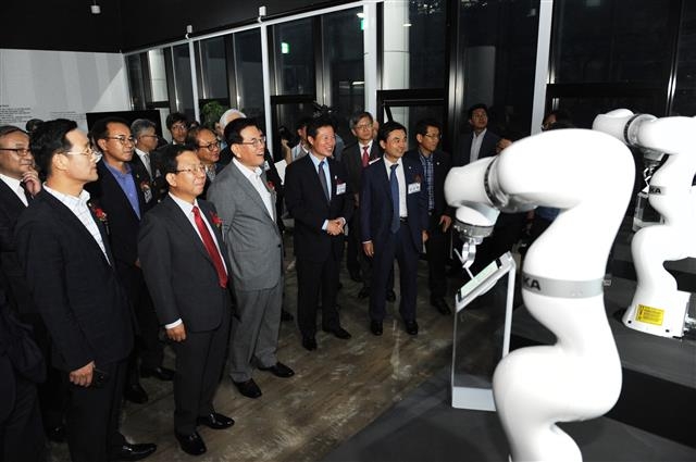 유덕열(앞줄 왼쪽 세 번째) 동대문구청장이 지난 5일 열린 콘텐츠 시연장 개관식에서 로봇팔 그림 시연을 보고 있다. 동대문구 제공