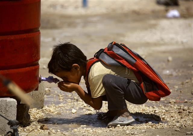 지난 8월 23일(현지시간) 시리아 락까 인근 아인이사 난민캠프 물탱크 앞에서 한 어린이가 쪼그려 앉은 채 물을 마시고 있다. 2011년 내전이 발발한 데다 극단주의 무장단체 이슬람국가(IS)까지 준동해 시리아 전 국토가 초토화됐고 전 국민의 절반 수준인 약 1000만명이 난민으로 전락했다. AFP 연합뉴스