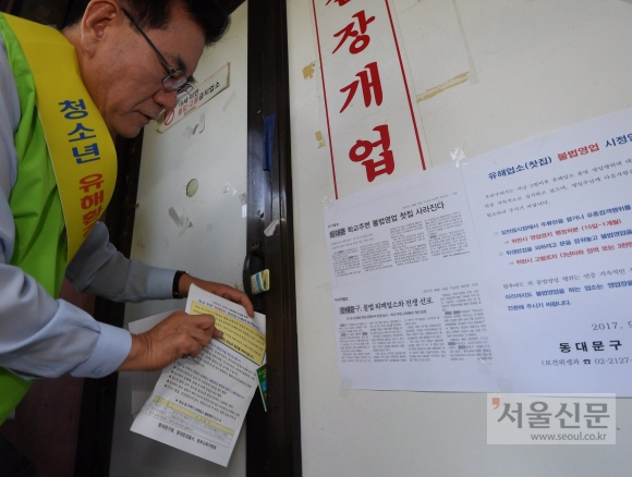유 구청장이 굳게 닫힌 한 업소 문틈 사이로 영업자제를 촉구하는 안내장을 집어넣고 있다.  박윤슬 기자 seul@seoul.co.kr