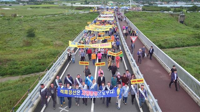 강정고령보 차량통행 추진위원회 회원들이 지난 11일 오후 달성군 다사읍~고령군 다산면을 잇는 우륵교에서 집회를 열고 차량 개통을 촉구하는 구호를 외치며 행진하고 있다. 고령군 제공