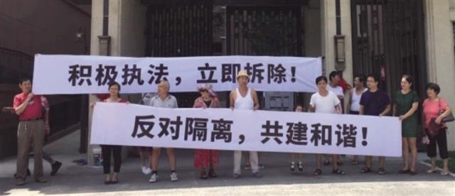 베이징시 차오양구의 ‘룽후톈푸’ 주택 단지에 사는 임대아파트 주민들이 시 당국에 담장 철거를 촉구하는 내용의 현수막을 들고 시위하는 모습. 바이두 캡처