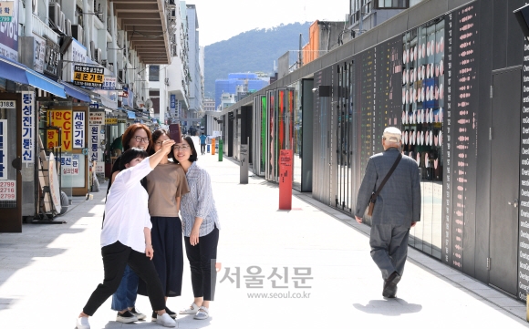 서울시가 세운상가 재생을 위한 1단계 사업으로 세운·청계·대림상가 건물 양쪽 자투리 땅 위로 2~3층 높이의 갑판(데크)을 세우고 건물과 건물 사이를 교량으로 이어 연결 보행로를 조성하면서 한쪽으로는 스타트업체들이 입주할 ‘메이커스 큐브’를 세웠다. 사진은 시민들이 세운상가 건물 데크 위에 만들어진 보행길에서 상가와 큐브를 배경으로 셀카를 찍고 있다.  이호정 전문기자 hojeong@seoul.co.kr