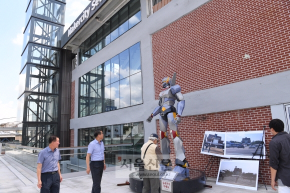 종묘를 바라보는 세운상가 정면 3층 정문 앞에 상가의 기술 장인들과 청년 작가들이 함께 만든 동작 조형물인 ‘세봇’을 시민들이 구경하고 있다. 세봇은 세운과 로봇의 합성어다.  이호정 전문기자 hojeong@seoul.co.kr