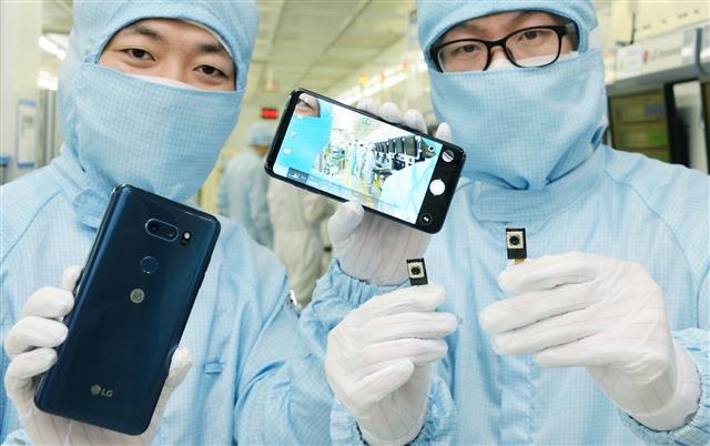지난 20일 광주광역시 하남공단 LG이노텍 생산라인의 직원들이 LG전자 ‘V30’에 장착되는 듀얼카메라 모듈을 들어 보이고 있다. LG전자 제공
