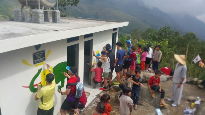 자비의 해우소 31호인 베트남 북서부 사파 근처 반광1 초등학교를 찾은 한국 달림이 일행들이 아이들이 지켜보는 가운데 담장에 그림을 그리고 있다. 
