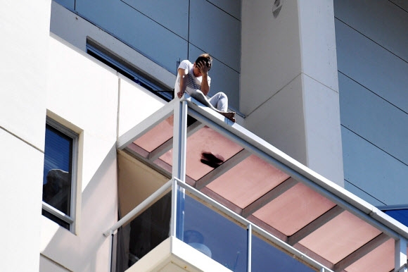 9일 호주 시드니 채스우드의 한 빌딩 꼭대기 층 차양 위에 한국인 남성 S씨가 위험하게 앉아 있다. 사진=EPA 연합뉴스