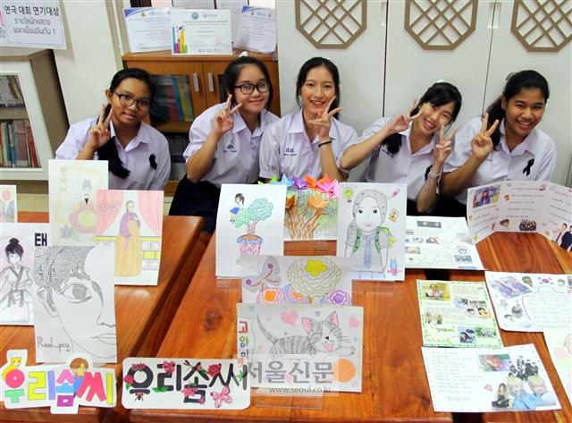 태국 싸라윗타라 학교 한국어반 5학년 학생들이 한국문화 수업 시간에 만든 그림들을 보여주면서 활짝 웃고 있다. 그림은 다양한 한글을 활용하거나 한국 문화를 그려 완성한 것들이다.