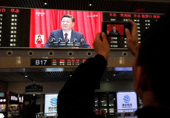 18일 랴오닝성 선양역의 스크린에 비친 시진핑 국가주석의 연설 모습을 한 시민이 카메라로 찍고 있는 모습. 선양 AFP 연합뉴스