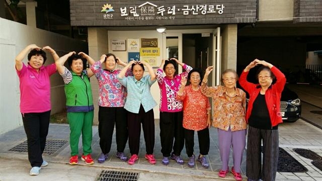 금천구의 홀몸 어르신 맞춤형 공공원룸인 ‘보린주택’ 앞에서 입주 어르신들이 두 팔로 하트를 그리며 환하게 웃고 있다. 금천구 제공