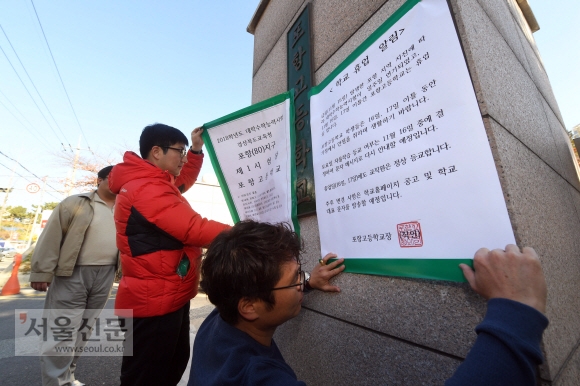 16일 수능시험장인 경북 포항시 포항고등학교에서 교직원들이 수능 관련 게시물을 없애고 학교 휴업을 알리는 게시물을 정문에 붙이고 있다.  정연호 기자 tpgod@seoul.co.kr