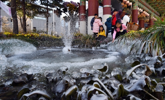 전국 대부분 지역 아침 기온이 영하권에 들면서 올 가을 들어 가장 추운 날씨를 보인 19일 서울 종로구 조계사 분수가 얼자 아이들이 신기한듯 고드름을 만져보고 있다.  박윤슬 기자 seul@seoul.co.kr