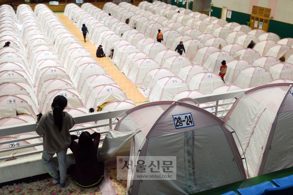 지진 피해 이재민들이 21일 경북 포항시 흥해 실내체육관에 마련된 220동의 사생활보호임시텐트로 거처를 옮기고 있다. 시는 건물 파손 여부 등에 대한 조사에서 파손 정도가 심한 이재민들을 우선적으로 선발했다. 박윤슬 기자 seul@seoul.co.kr