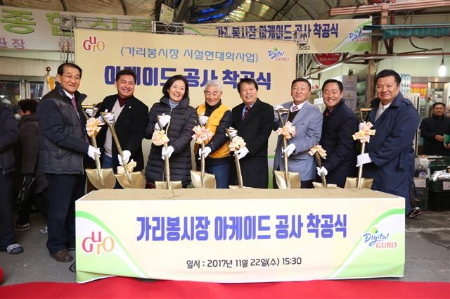 이성(오른쪽 네 번째) 구로구청장이 지난 22일 가리봉시장 아케이드 공사 착공식에 참석해 삽을 들고 포즈를 취하고 있다. 왼쪽 세 번째는 박영선 더불어민주당 의원. 구로구 제공