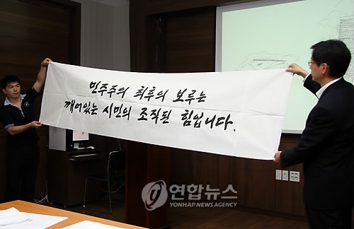 경남 김해시 진영읍 봉하마을 마을회관에서 열린 고 노 전 대통령 묘역 안장계획 브리핑에서 묘역을 덮을 강판에 새겨진 신영복 선생의 원본 글씨를 노 전 대통령 비서진이 들어보이고 있다. 연합뉴스