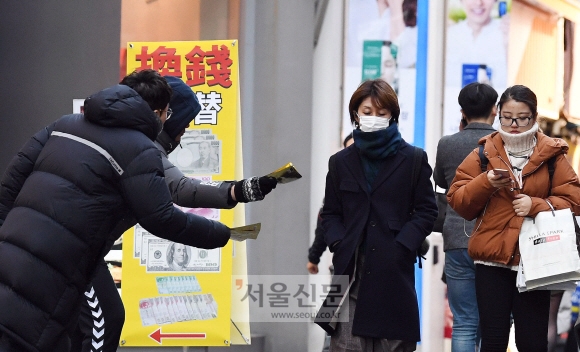 롱패딩을 입고 장갑을 낀 호객꾼들이 8일 서울 중구 명동거리를 지나는 이들에게 사은품인 마스크팩을 내밀며 호객 행위를 하고 있다. 박윤슬 기자 seul@seoul.co.kr