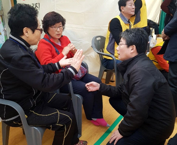 바른정당 유승민(오른쪽) 대표가 8일 경북 포항 북구 흥해체육관에 마련된 지진 대피소를 찾아 무릎을 꿇고 앉아 이재민의 이야기를 듣고 있다. 포항 연합뉴스