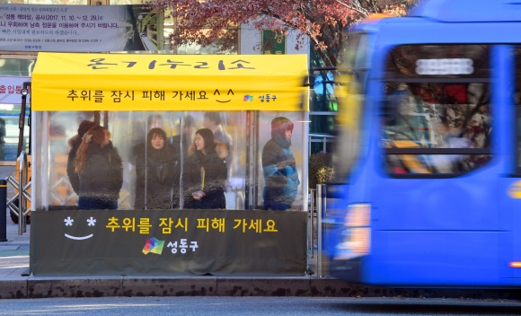 추위가 맹위를 떨친 13일 서울 성동구청 앞 버스정류장에 설치된 추위대피소 ‘온기누리소’에서 시민들이 추위를 피하며 버스를 기다리고 있다. ‘온기누리소’는 성동구가 버스정류장에 설치한 추위대피소로 현재  17개가 설치되어 있고 앞으로 11개가 추가로 설치될 예정이다. 2017. 12. 13 정연호 기자 tpgod@seoul.co.kr