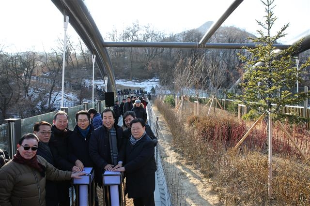 지난 13일 서울 서대문구 현저동 안산과 종로구 무악동 인왕산을 잇는 무악재 하늘다리 개통 행사에 참석한 김영종(왼쪽 네 번째부터) 종로구청장, 문석진 서대문구청장, 김호진 서대문구의회의장, 김복동 종로구의회의장이 기념 조명 버튼을 누르고 있다. 서대문구 제공