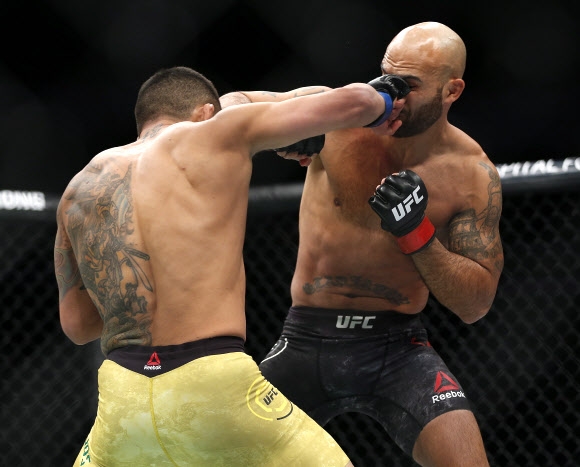 16일(현지시간) 캐나다 매니토바주 위니펙에서 열린 ‘UFC 파이트 나이트’에서 하파엘 도스 안요스와 로비 라울러가 서로의 얼굴을 향해 펀치를 날리고 있다. AP 연합뉴스