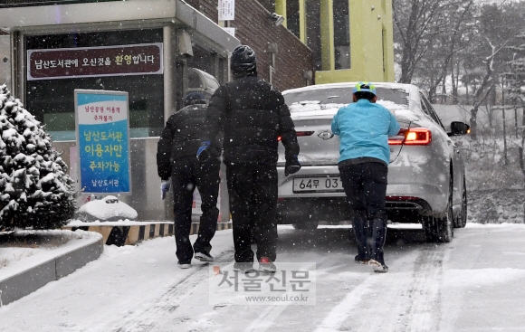 폭설이 내린 18일 서울 남산도서관에서 관계자들 미끄러진 차량을 밀고 있다. 2017.12.18  박지환기자 popocar@seoul.co.kr