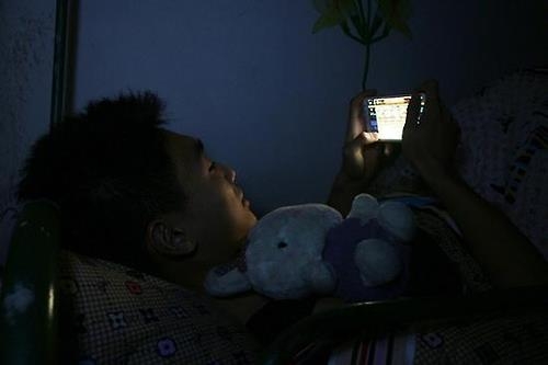 최근 중국 인터넷에는 독거청년의 외로움을 나타내는 사진과 만화가 넘쳐난다. 한 청년이 불 꺼진 방에서 스마트폰을 보는 모습.