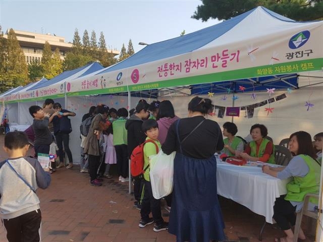지난 10월 광진구 능동로 분수광장에서 열린 ‘자원봉사 박람회’를 찾은 주민들이 전통한지 잠자리 만들기 등 다양한 체험을 하고 있다.  광진구 제공