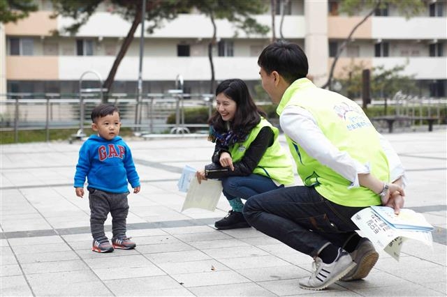 천호3동 찾동 우동주들이 눈높이를 맞추기 위해 쪼그려 앉아 지역 어린아이를 보며 웃고 있다. 서울시 제공