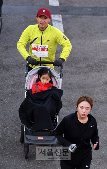 한 남성 참가자가 유모차에 딸을 태우고 마라톤 코스를 달리고 있다. 활기차고 건강한 새해를 맞이하기 위해 가족 단위로 참가한 사람들이 많았다. 정연호 기자 tpgod@seoul.co.kr