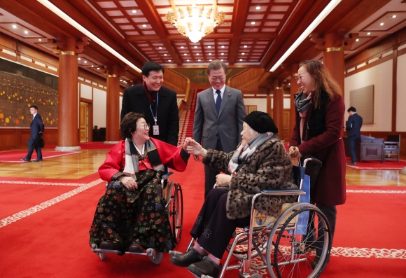 문재인 대통령이 4일 청와대로 일본군 위안부 피해자 할머니 8명을 초청해 오찬을 함께 한 뒤 휠체어를 탄 이용수(왼쪽)·안점순(오른쪽) 할머니 등을 배웅하며 환하게 웃고 있다. 청와대 제공