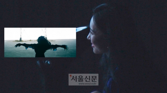 선미가 자신의 신곡 ‘주인공’ 뮤직비디오를 시청하며 미소를 지어보이고 있다.